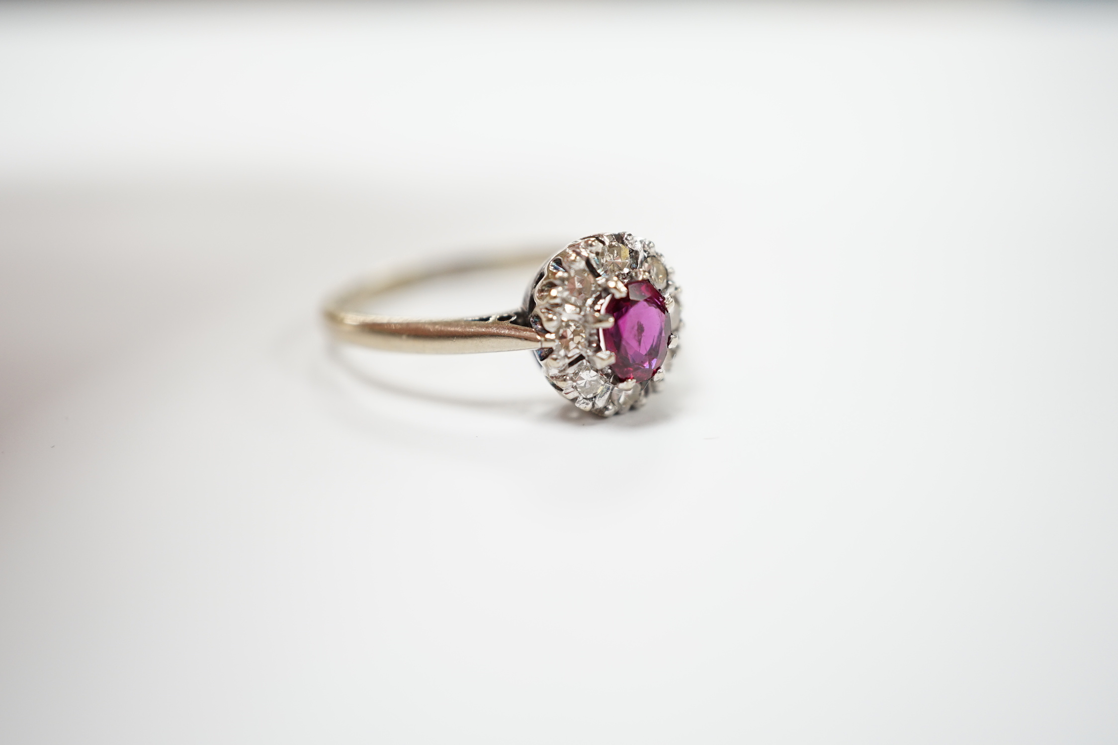 A 18ct white, ruby and diamond set oval cluster ring, size Q/R, gross weight 4.2 grams.